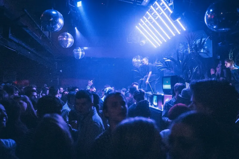 Crowd dancing under blue lights at a concert.